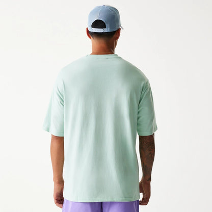 The Male model is wearing New Era Crest Pastel Green Oversized T-Shirt 2