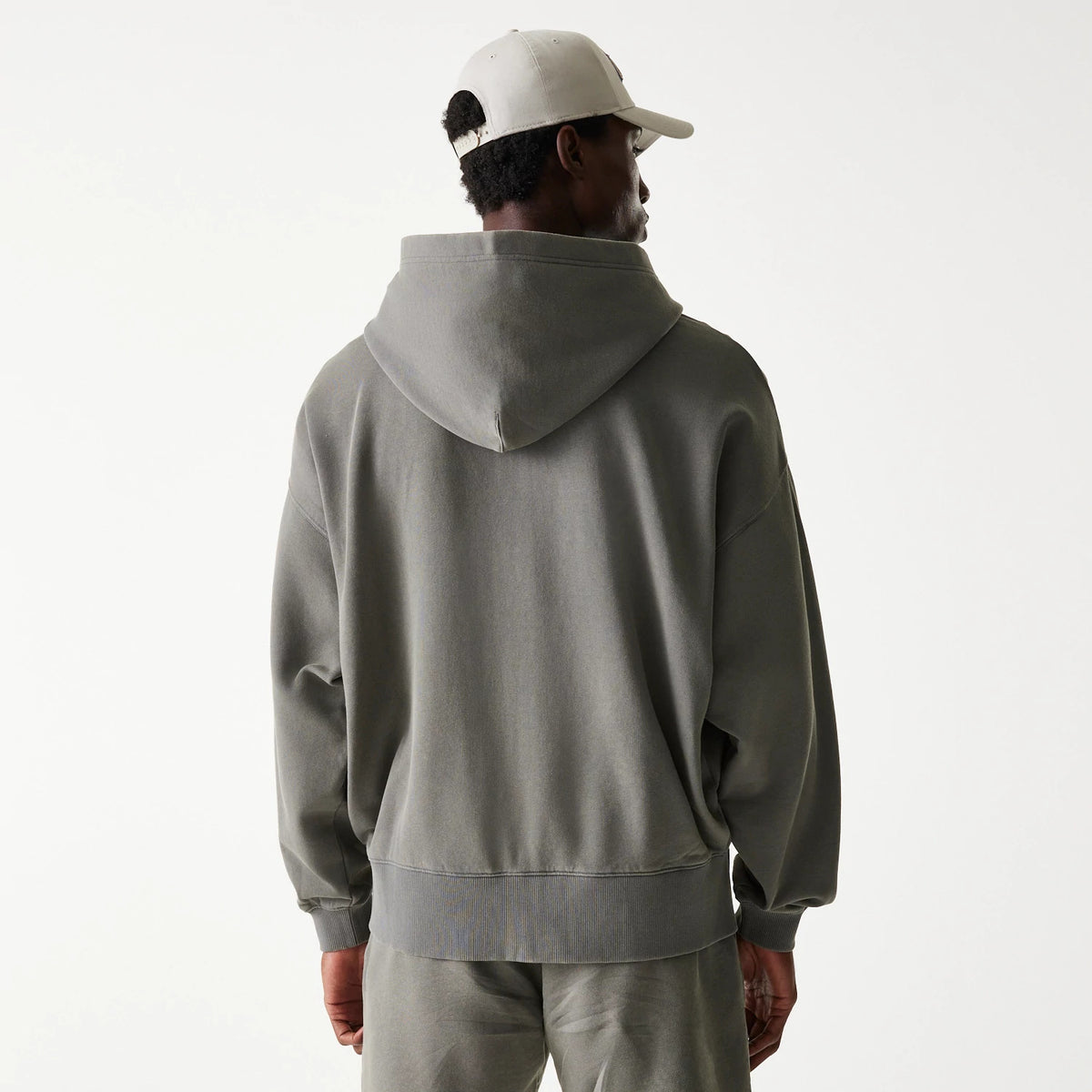 New Era LA Lakers NBA Washed Grey Full Zip Hoodie, rear view showing the relaxed fit grey hoodie with a roomy hood draping down the back, ribbed cuffs and hem, and a white debossed New Era logo on a cream cap worn by the model.