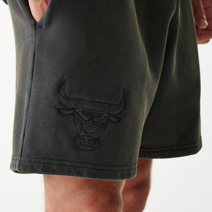 New Era Chicago Bulls NBA Washed Grey Shorts, side view showing the dark grey fabric with a raised Chicago Bulls logo on the lower leg, emphasising the relaxed fit and hem stitching detail near the knee.