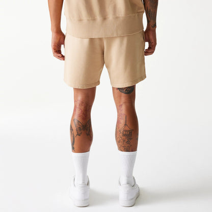 New Era Chicago Bulls NBA Washed Beige Shorts, rear view showing the soft beige colour and relaxed fit, with a straight hem falling above the knee, worn with white socks and trainers against a plain background.