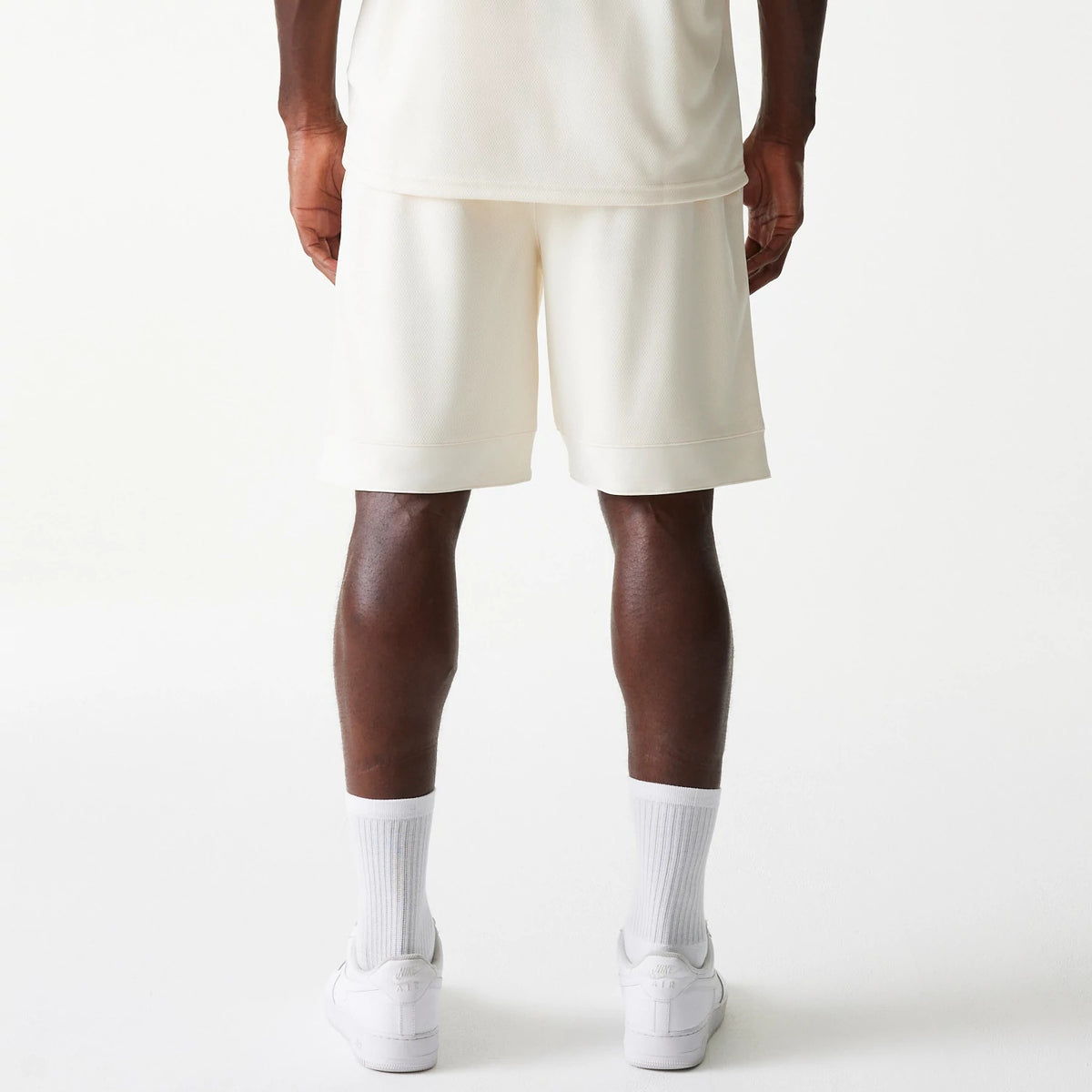 New Era LA Lakers NBA Tonal Open White Mesh Shorts, rear view showing the plain white shorts with a loose fit just above the knee, straight hem, and white socks paired with white shoes visible below.