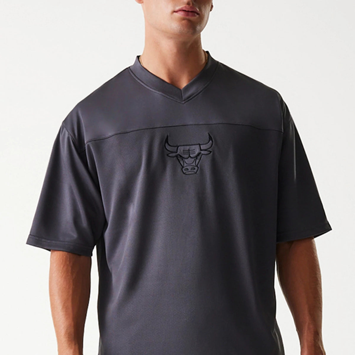 New Era Chicago Bulls NBA Tonal Dark Grey Mesh Jersey, front view on a model showing the embroidered Bulls logo centred on the chest with a V-neck design and short sleeves.