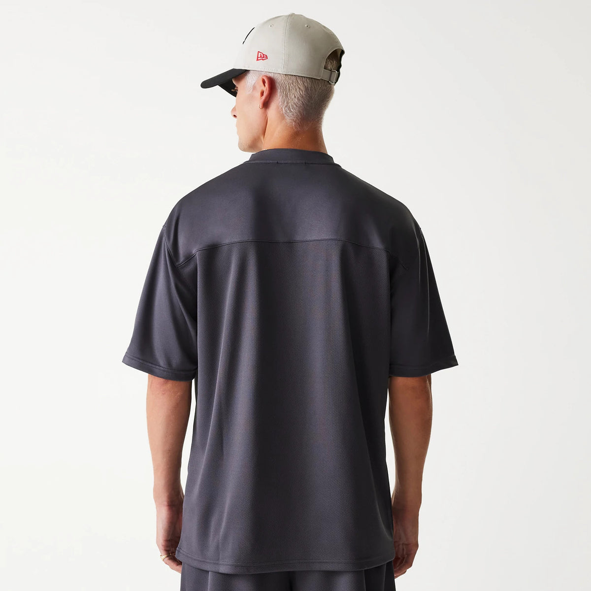 New Era Chicago Bulls NBA Tonal Dark Grey Mesh Jersey, back view on a model wearing a stone-grey cap with a red New Era flag logo on the left side, highlighting the jersey's dark grey mesh fabric and relaxed fit.