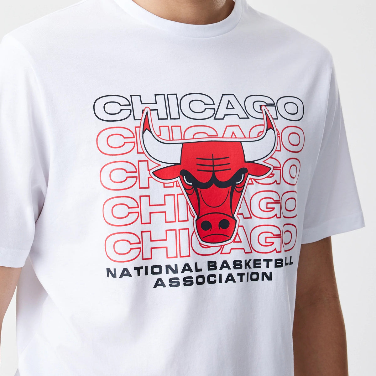 New Era Chicago Bulls NBA Stack Wordmark White T-Shirt, front view showing a bold red and black Chicago Bulls logo centred on the chest with stacked wordmark repetition, beneath text reading National Basketball Association in black.