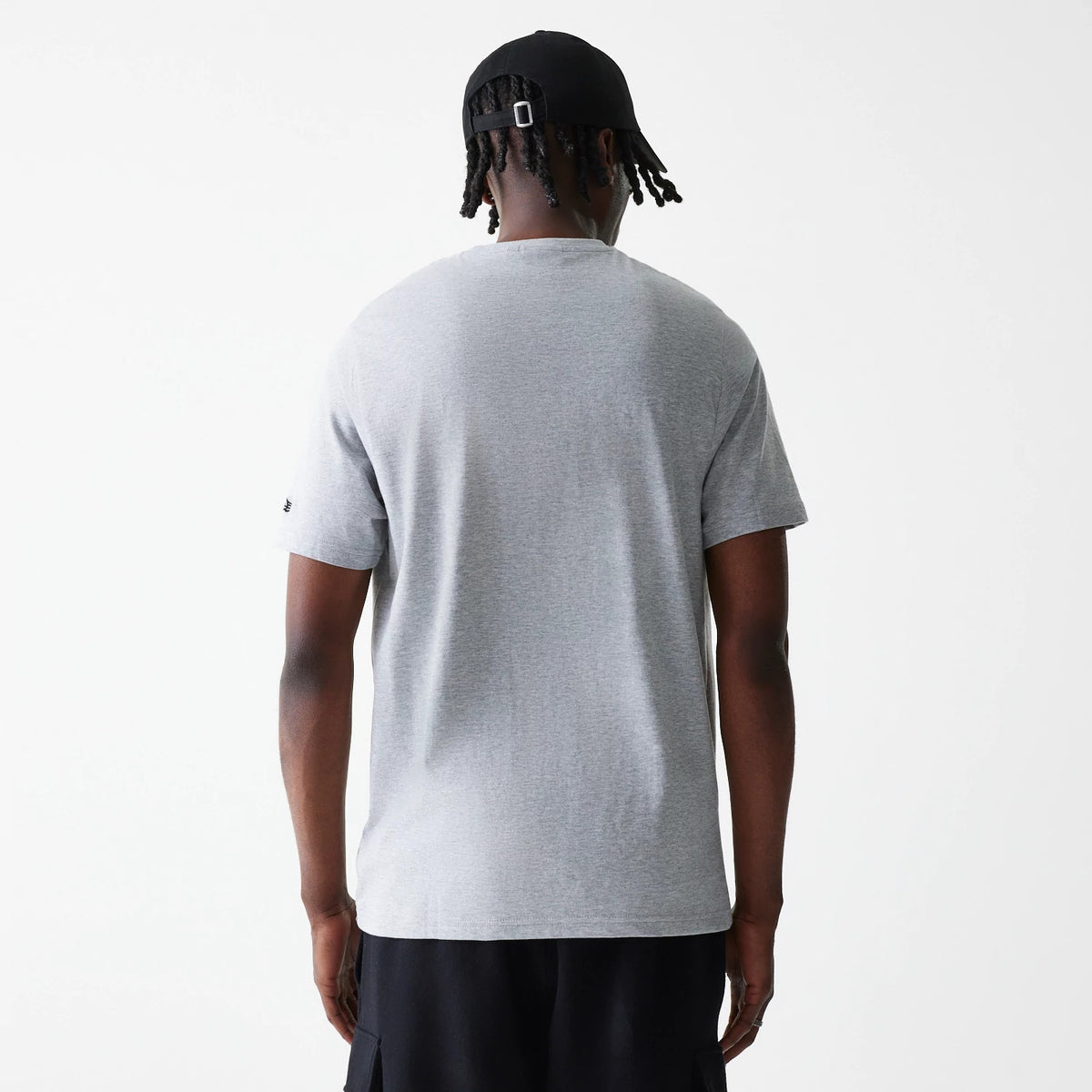 New Era LA Lakers NBA Logo Grey T-Shirt, rear view showing the plain grey back of the T-shirt, worn by a person in black shorts and a black cap with a buckle on the back, small logo detail on the left sleeve.