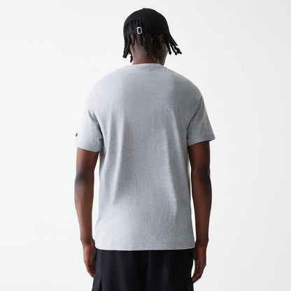 New Era LA Lakers NBA Logo Grey T-Shirt, rear view showing the plain grey back of the T-shirt, worn by a person in black shorts and a black cap with a buckle on the back, small logo detail on the left sleeve.