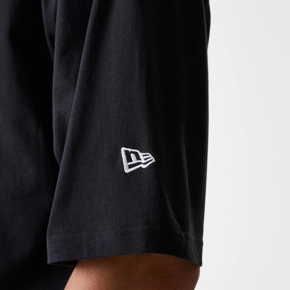 New Era New York Yankees MLB League Essential Black Oversized T-Shirt, side view showing the black short sleeve with a white embroidered New Era logo near the hem and the soft drape of the fabric.