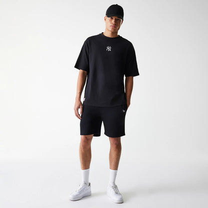 New Era New York Yankees MLB League Essential Black Oversized T-Shirt, on-model view showing the black oversized T-shirt with a white embroidered New York Yankees logo on the chest, paired with black shorts and a black cap.