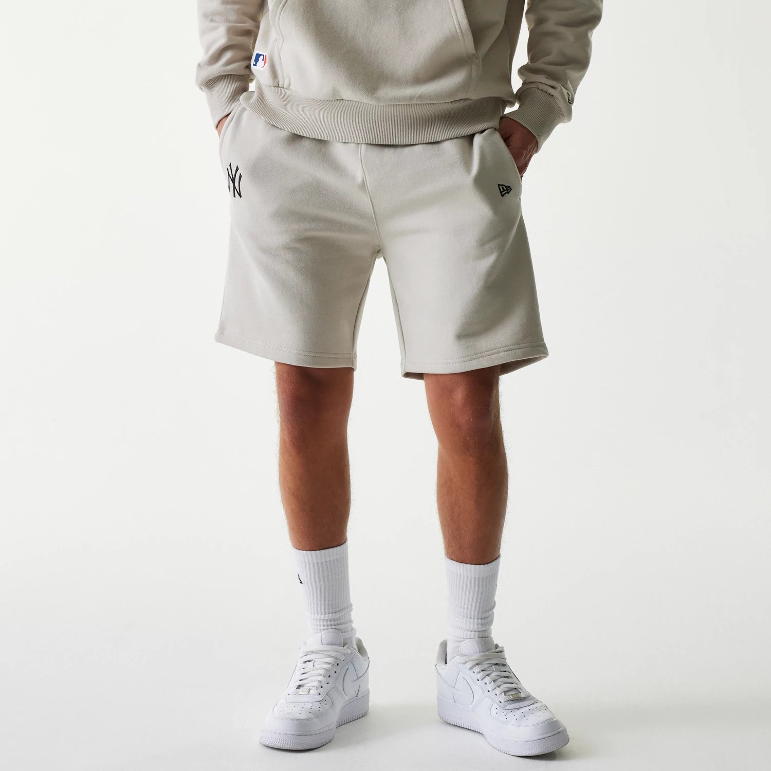 The Male model is wearing New York Yankees MLB League Essential Midi Cream Shorts 1