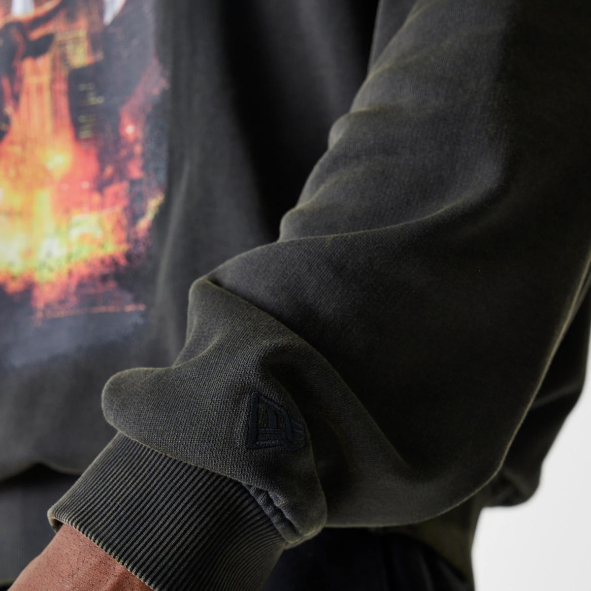 New Era Chicago Bulls NBA Washed Graphic Grey Oversized Crew Neck Sweater, close-up showing the embroidered New Era flag logo on the sleeve cuff and vibrant graphic print on the chest.