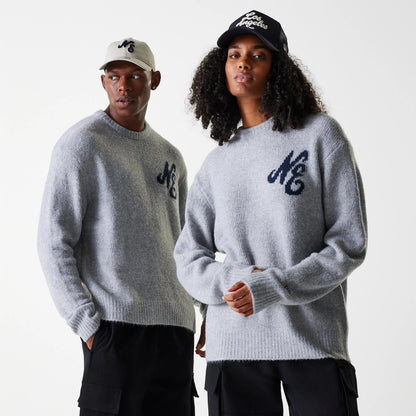 New Era Knit Grey Oversized Knit Sweater, on-model view showing two individuals wearing grey sweaters with navy NC logos on the chest, paired with black cargo trousers and New Era caps.