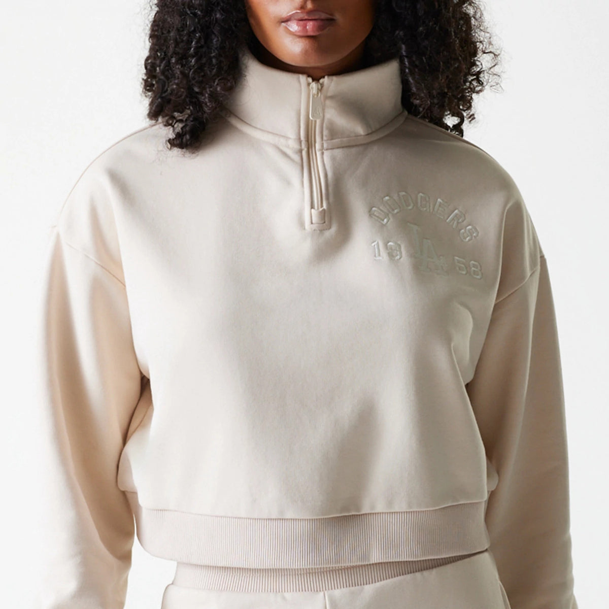 New Era LA Dodgers Womens MLB Tonal Light Beige Cropped 1/4 Zip Sweater, front view on a model showing the embossed Dodgers logo and 1958 text on the left chest, with a ribbed hem and high collar.