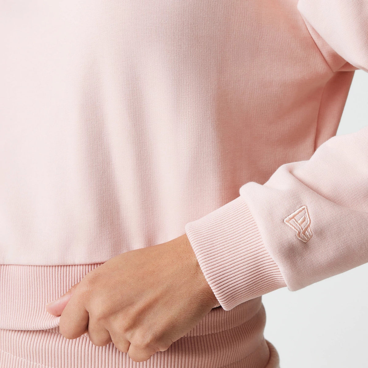 New Era New York Yankees Womens MLB Tonal Pastel Pink Cropped 1/4 Zip Sweater, close-up view showing the ribbed hem and cuff with an embroidered New Era flag logo on the sleeve above the wrist.