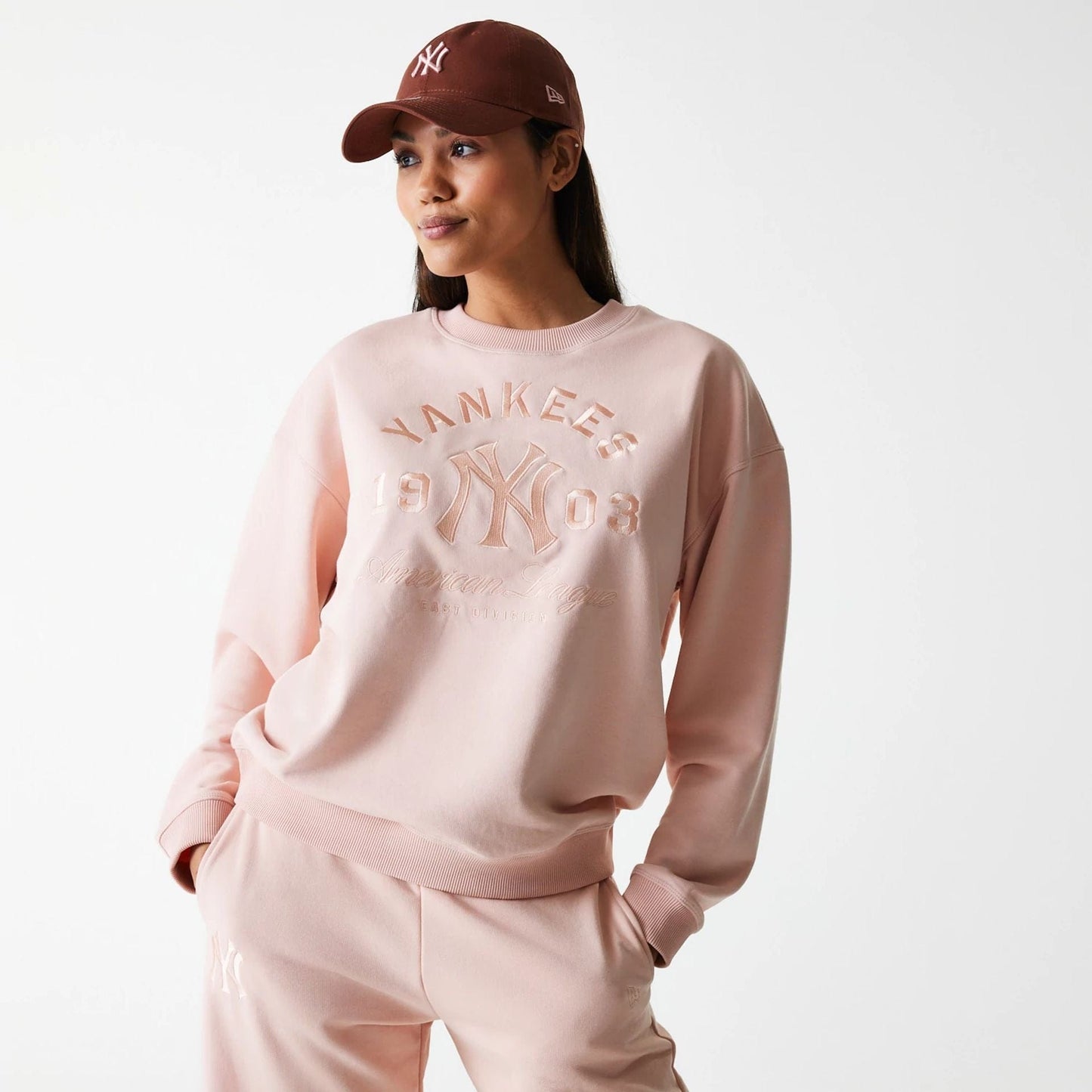 The Female model is wearing New York Yankees Womens MLB Tonal Graphic Pastel Pink Oversized Crew Neck Sweater 1