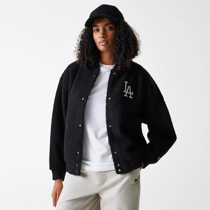 New Era LA Dodgers Womens MLB Black Oversized Sherpa Bomber Jacket, on-model view showing the black textured jacket with white LA logo on the left chest, black cuffs and hem, silver snap buttons, and a raised New Era logo on a black cap.