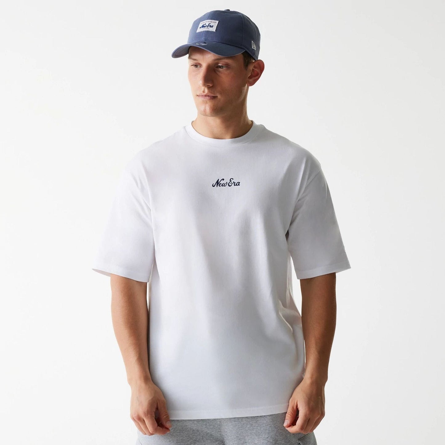 The Male model is wearing New Era Trucker Patch White Oversized T-Shirt 1