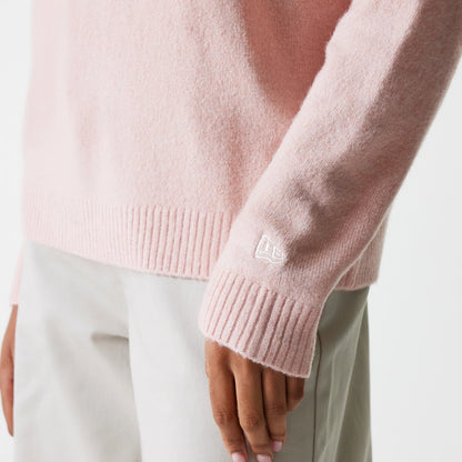 New Era New York Yankees Womens MLB Knit Pastel Pink Crew Neck Sweater, close-up of the lower sleeve and hem showing the New Era flag logo embroidered in white on the ribbed cuff, worn with light grey trousers.