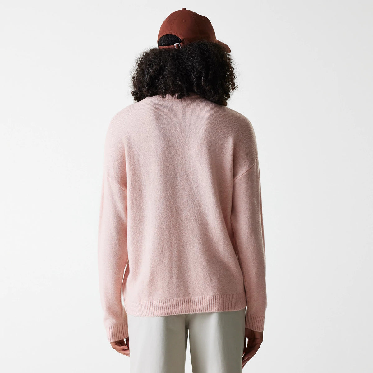 New Era New York Yankees Womens MLB Knit Pastel Pink Crew Neck Sweater, back view on a model wearing a brown cap, displaying the soft texture and relaxed fit with ribbed cuffs and hem against the light background.