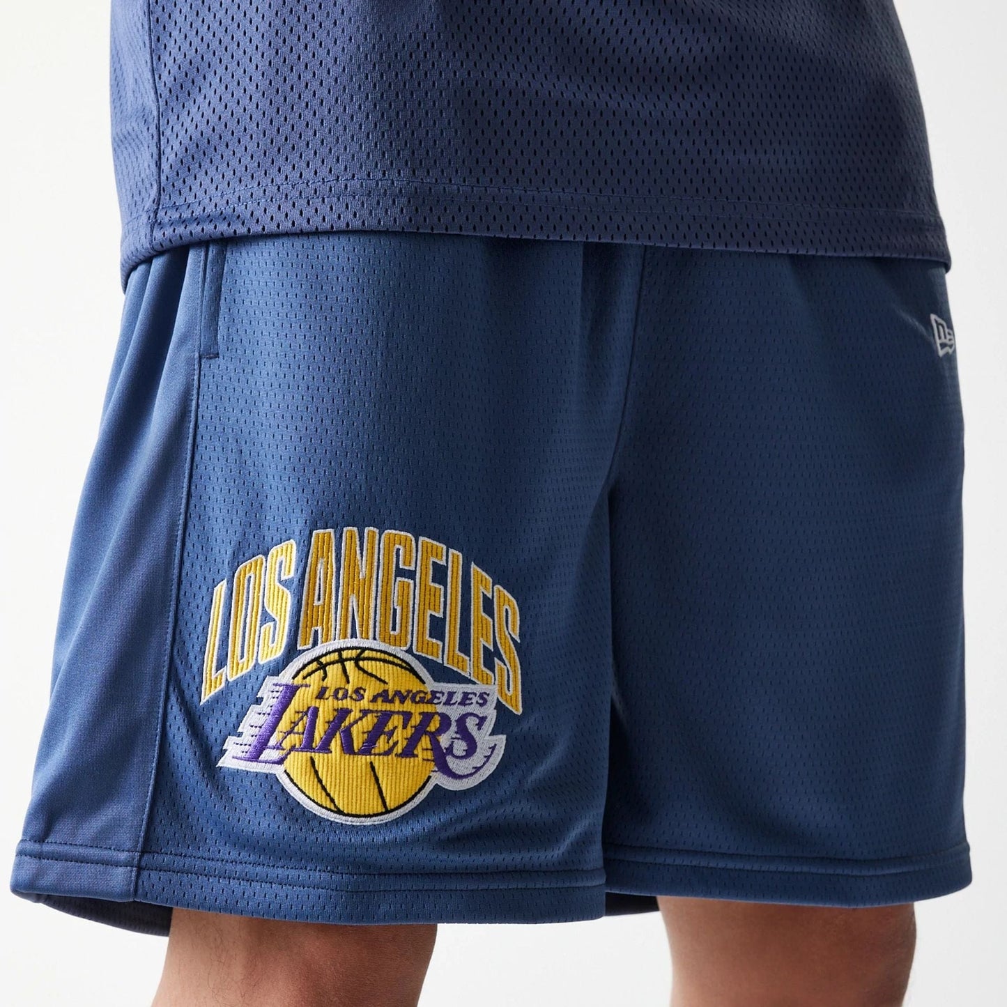 The Male model is wearing LA Lakers NBA Arch Graphic Dark Blue Mesh Shorts 3