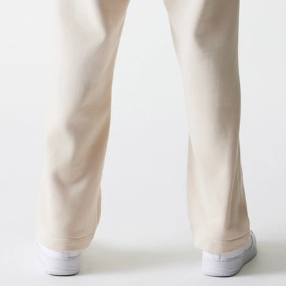 New Era Light Beige Straight Leg Joggers, rear view on a model showing the relaxed fit and straight leg design extending down to white sneakers, highlighting the soft light beige fabric.