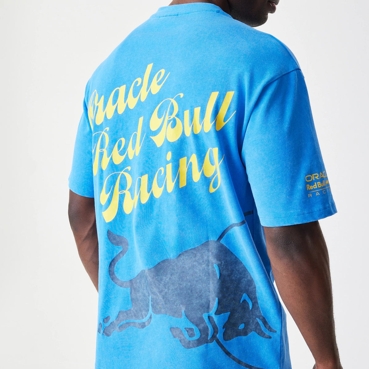 New Era Red Bull Racing Back Graphic Blue Oversized T-Shirt, back view on-model showing large yellow script lettering Oracle Red Bull Racing across the upper back and a graphic of a charging bull, with a smaller logo on the sleeve.