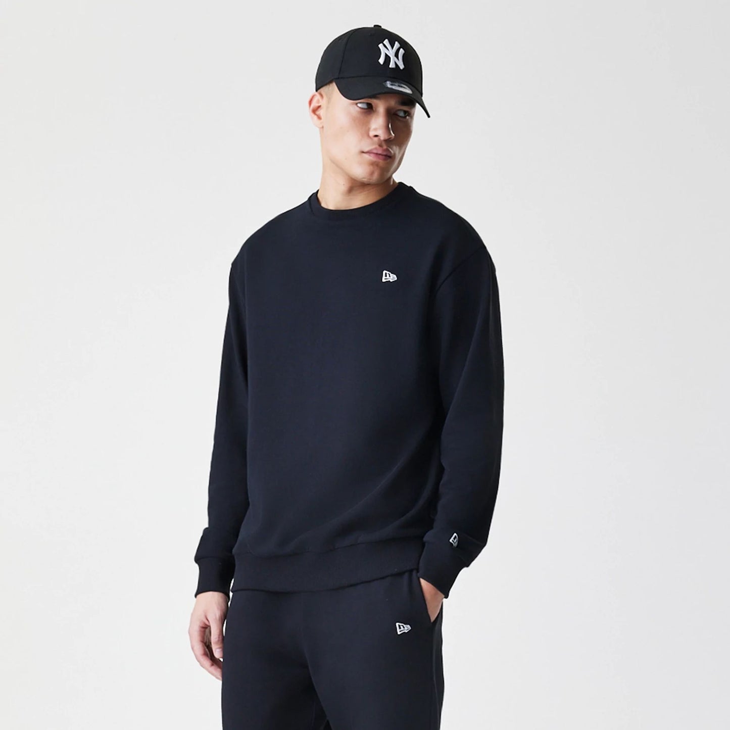 The Male model is wearing New Era Premium Essential Black Oversized Crew Neck Sweater 3