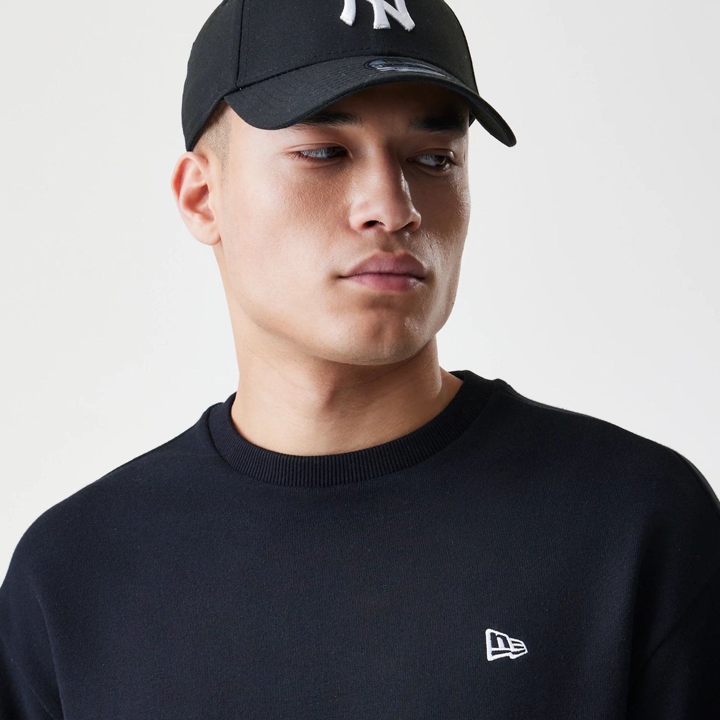 The Male model is wearing New Era Premium Essential Black Oversized Crew Neck Sweater 4