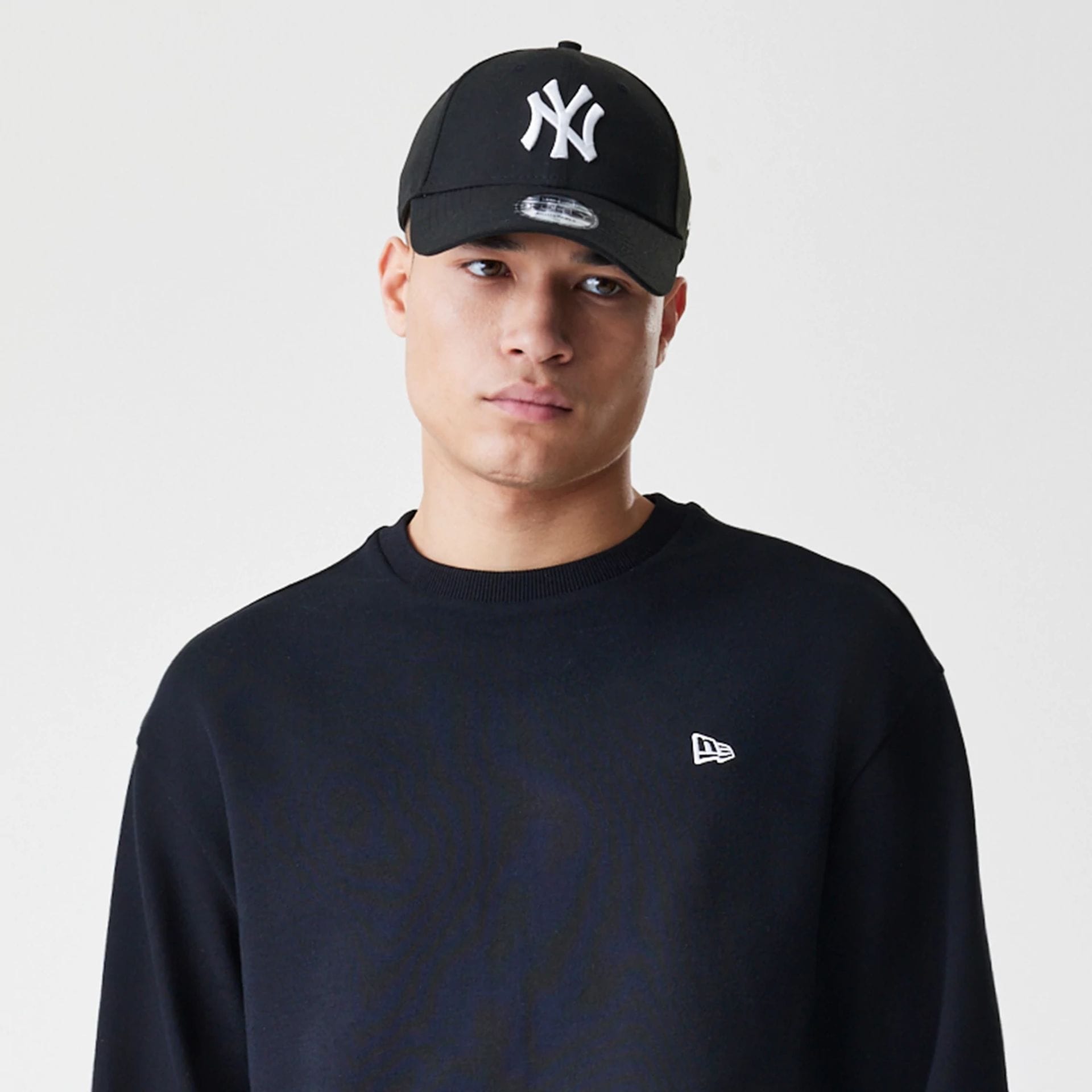The Male model is wearing New Era Premium Essential Black Oversized Crew Neck Sweater 6
