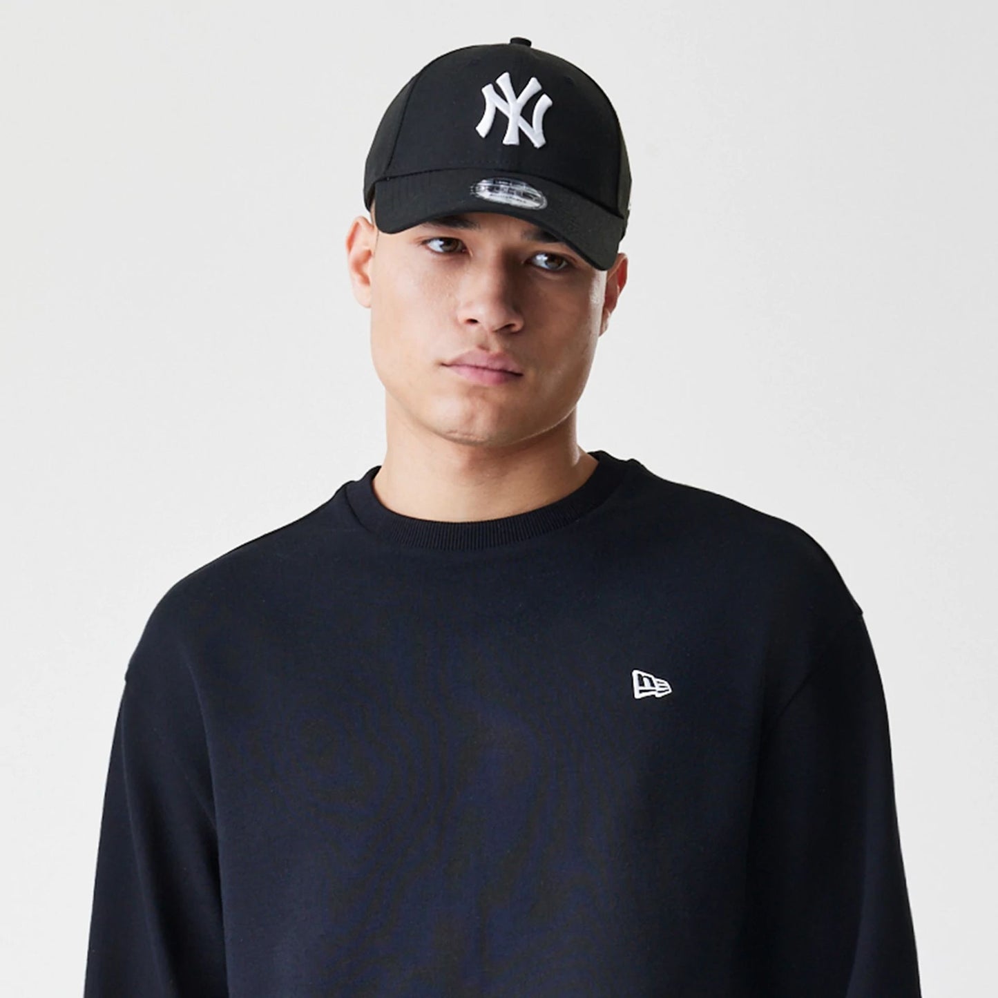 The Male model is wearing New Era Premium Essential Black Oversized Crew Neck Sweater 6