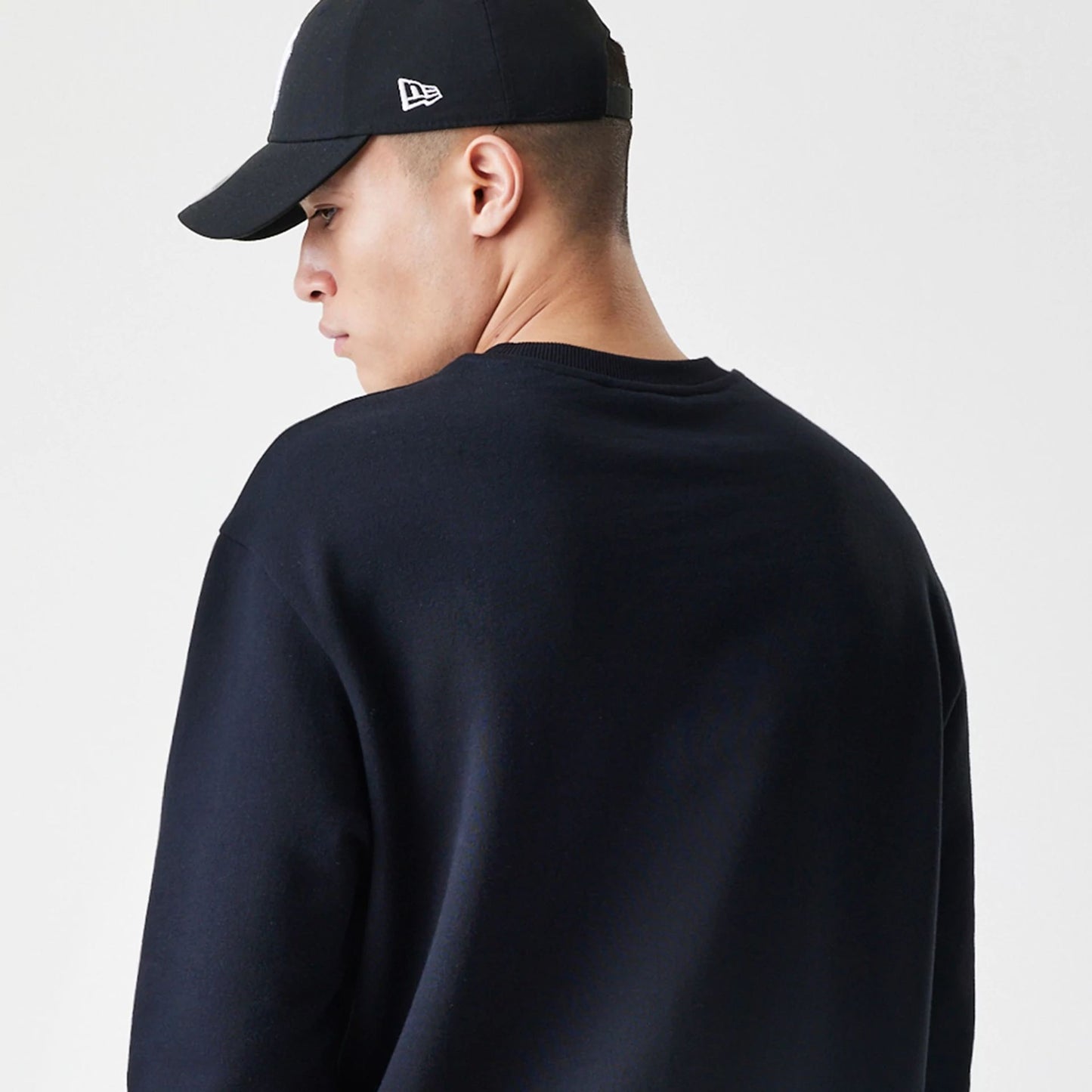 The Male model is wearing New Era Premium Essential Black Oversized Crew Neck Sweater 7