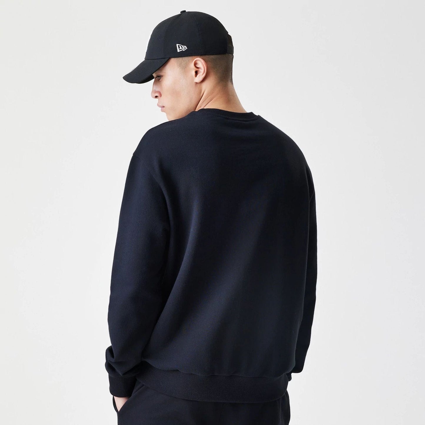 The Male model is wearing New Era Premium Essential Black Oversized Crew Neck Sweater 2