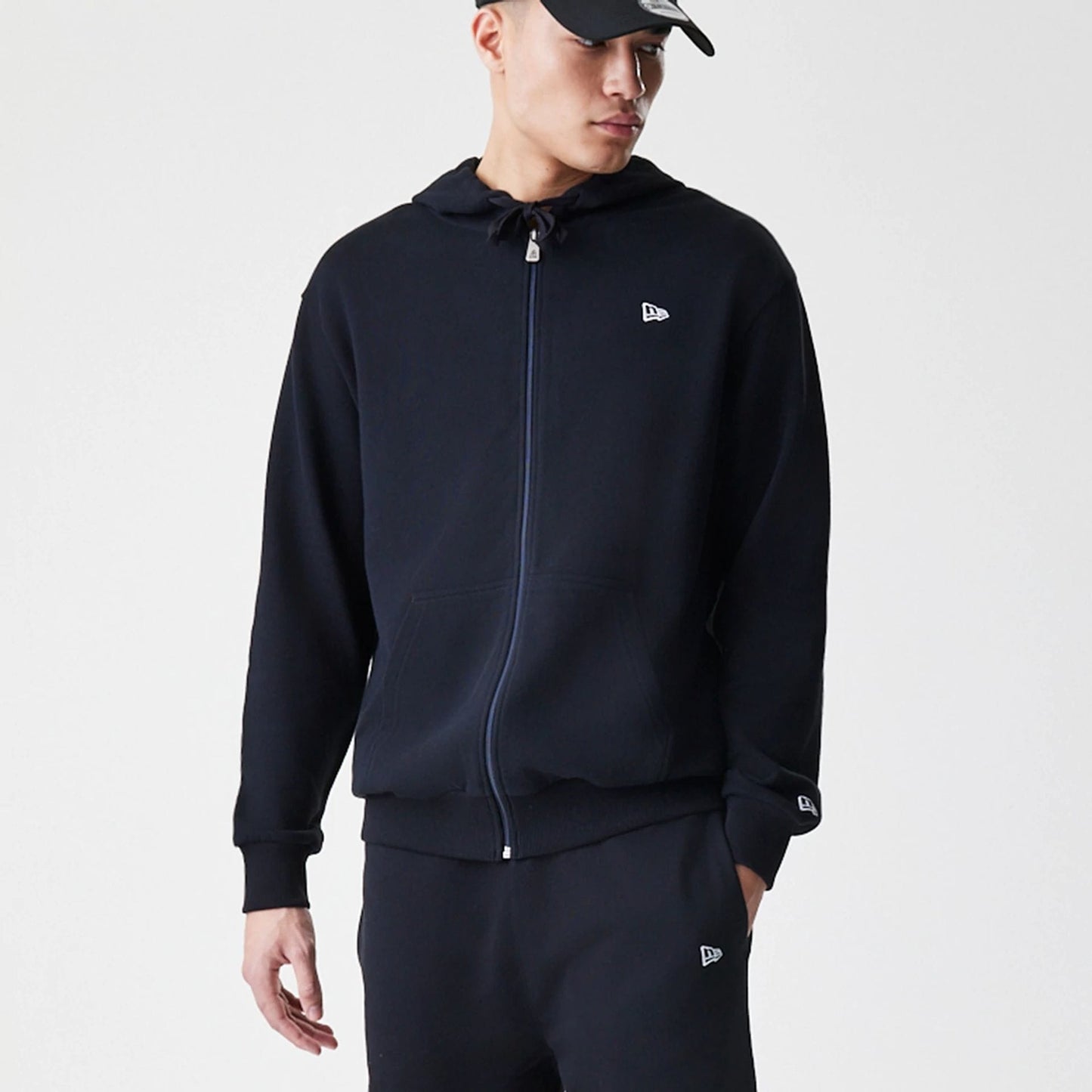 The Male model is wearing New Era Premium Essential Black Oversized Full Zip Hoodie 3