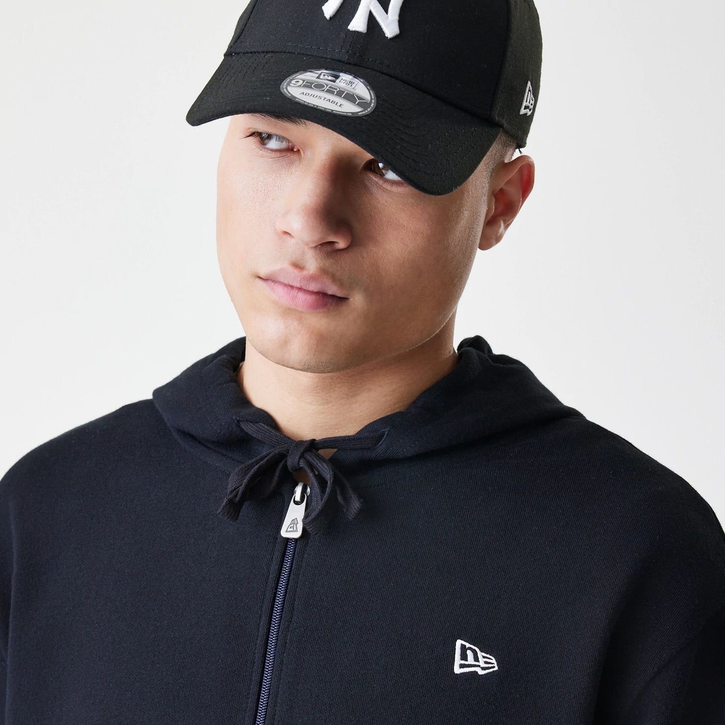 The Male model is wearing New Era Premium Essential Black Oversized Full Zip Hoodie 4