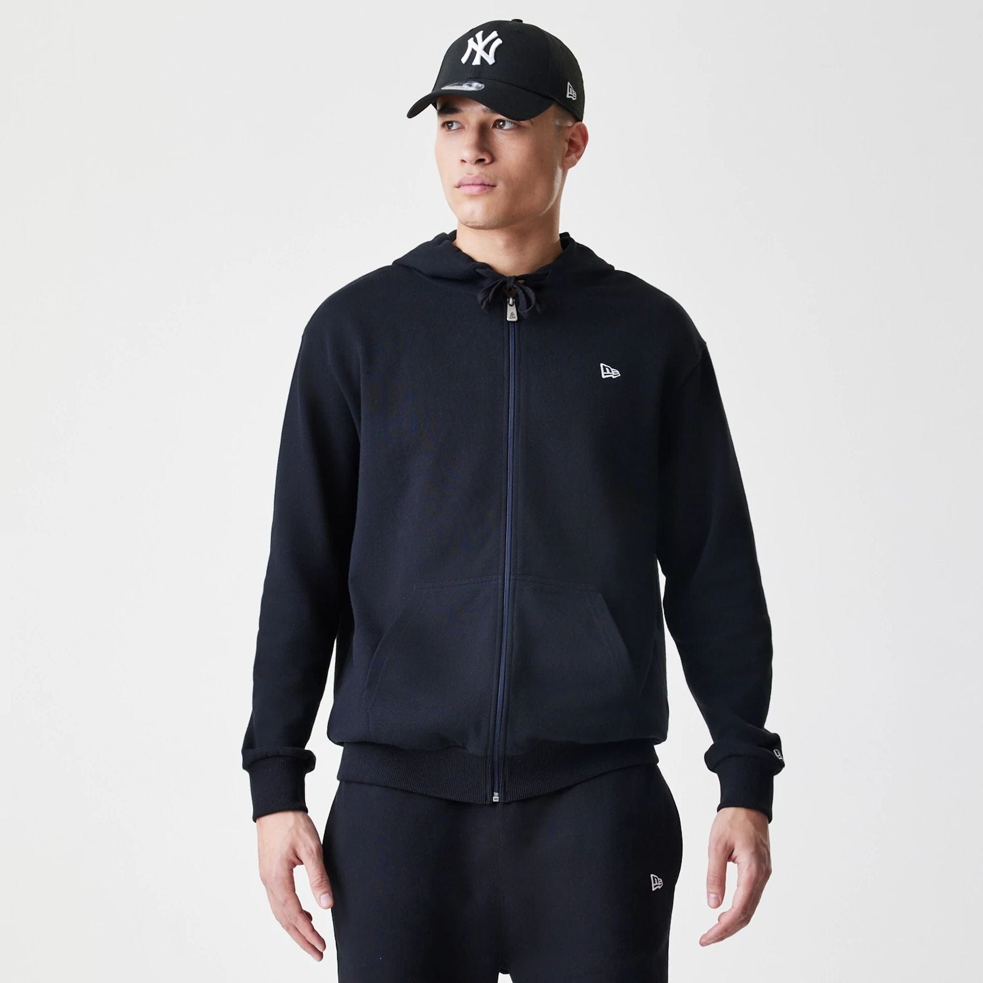 The Male model is wearing New Era Premium Essential Black Oversized Full Zip Hoodie 1
