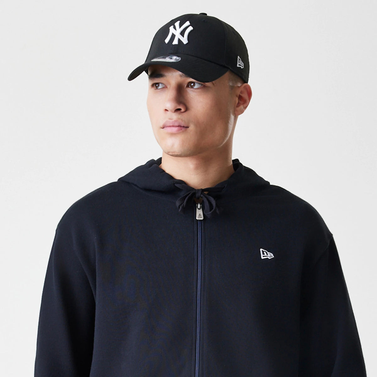 The Male model is wearing New Era Premium Essential Black Oversized Full Zip Hoodie 6