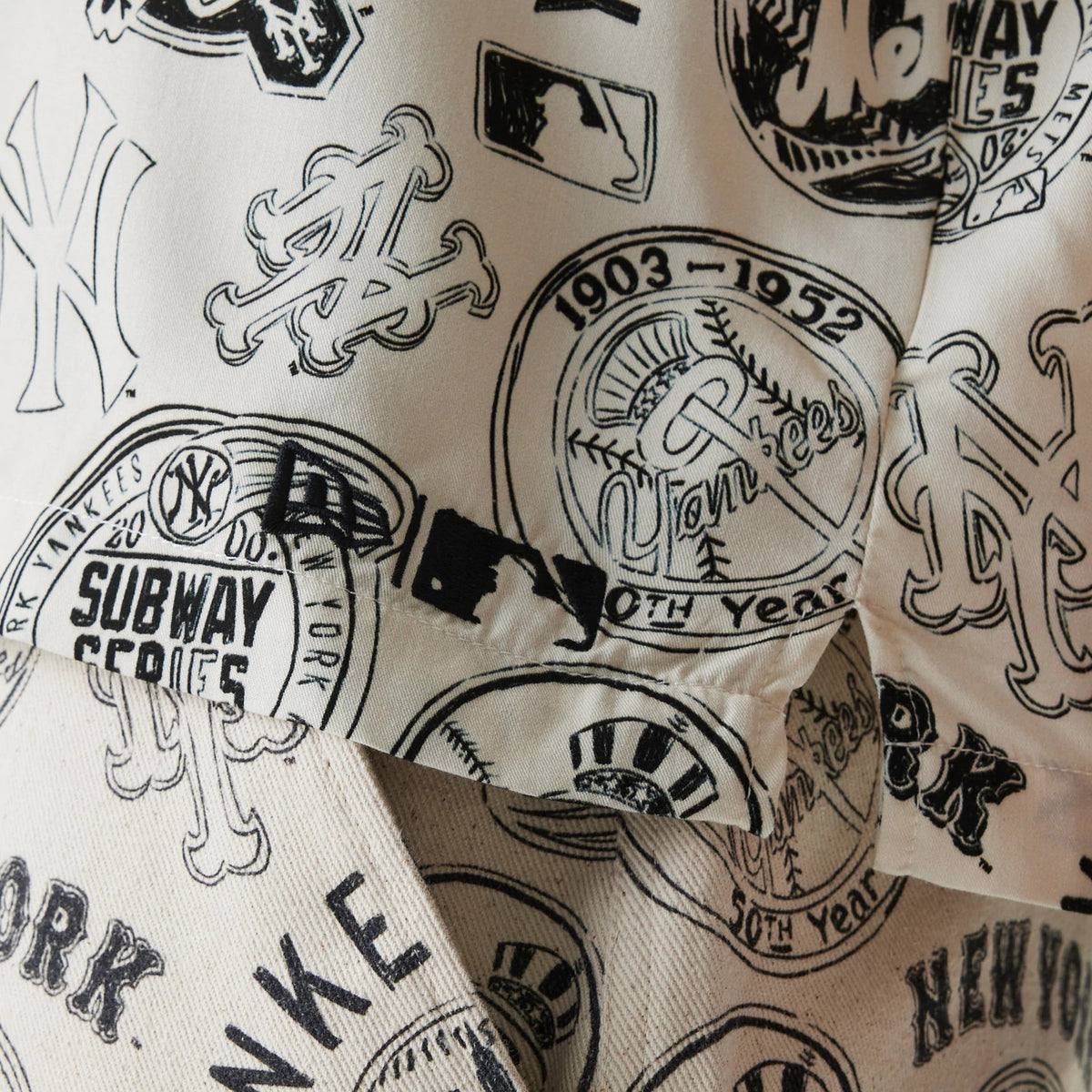New Era MLB Subway Series All Over Print Open White Short Sleeve Shirt, close-up showing various black and white logos including New York Yankees and Mets emblems, Subway Series text, and a vintage Yankees 50th Year design on the fabric.