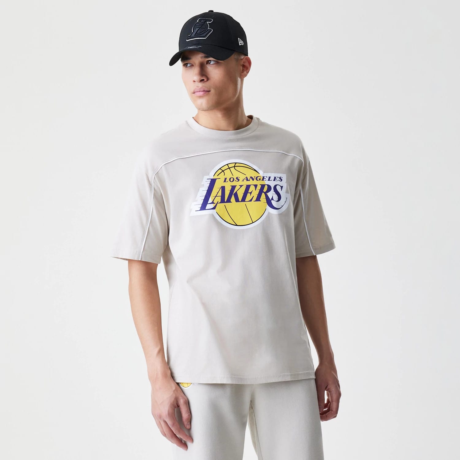 The Male model is wearing LA Lakers NBA Piping Light Beige Oversized T-Shirt 5