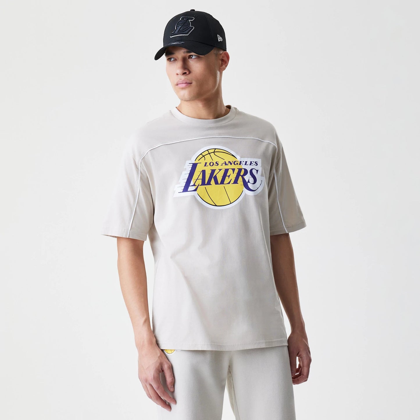 The Male model is wearing LA Lakers NBA Piping Light Beige Oversized T-Shirt 5