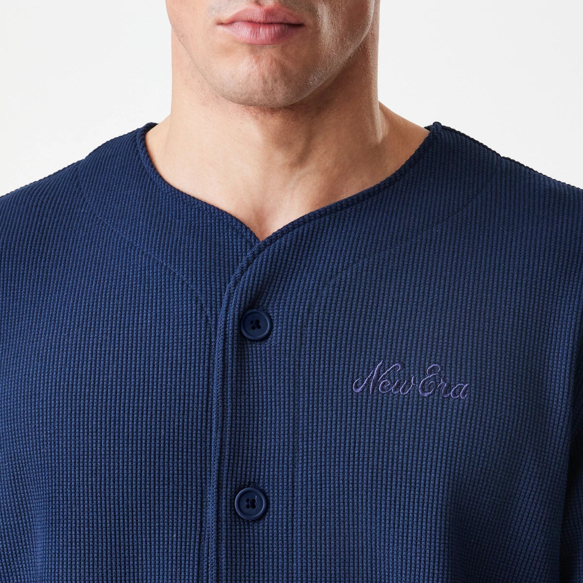 New Era Waffle Navy Jersey, front view showing navy waffle texture fabric with a button-up collar and embroidered New Era script logo on the left chest, worn by a model.