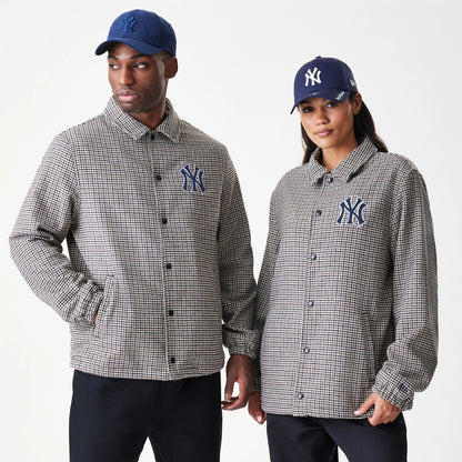New Era New York Yankees MLB Check Brown Jacket, front view on-model displaying the check pattern with an embroidered Yankees logo on the left chest, featuring a button closure and long sleeves, paired with a navy cap with an embroidered logo.