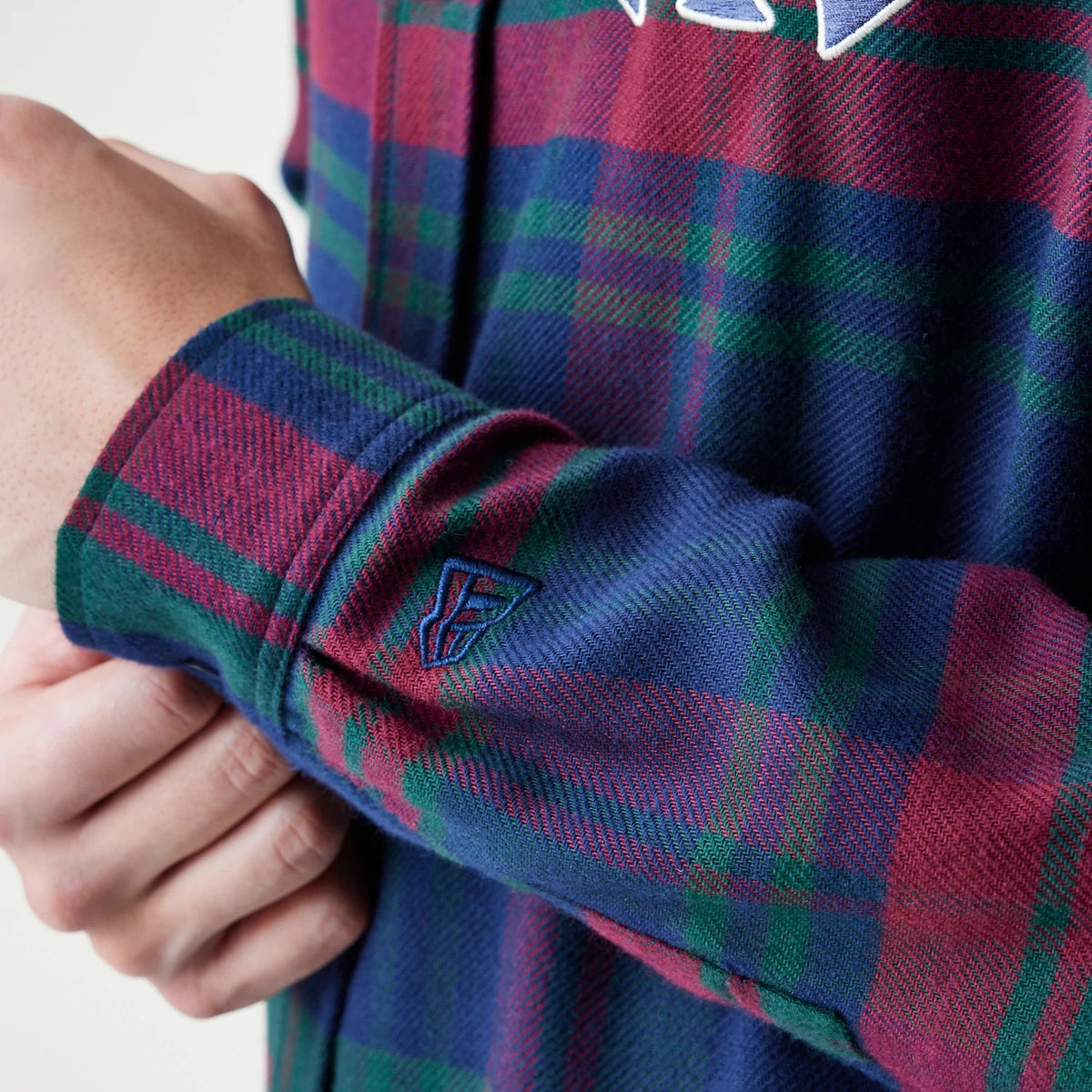 New Era New York Yankees MLB Check Navy Long Sleeve Shirt, close-up showing the embroidered New Era flag logo on the blue, red, and green check pattern sleeve, with white and navy Yankees lettering on the torso.