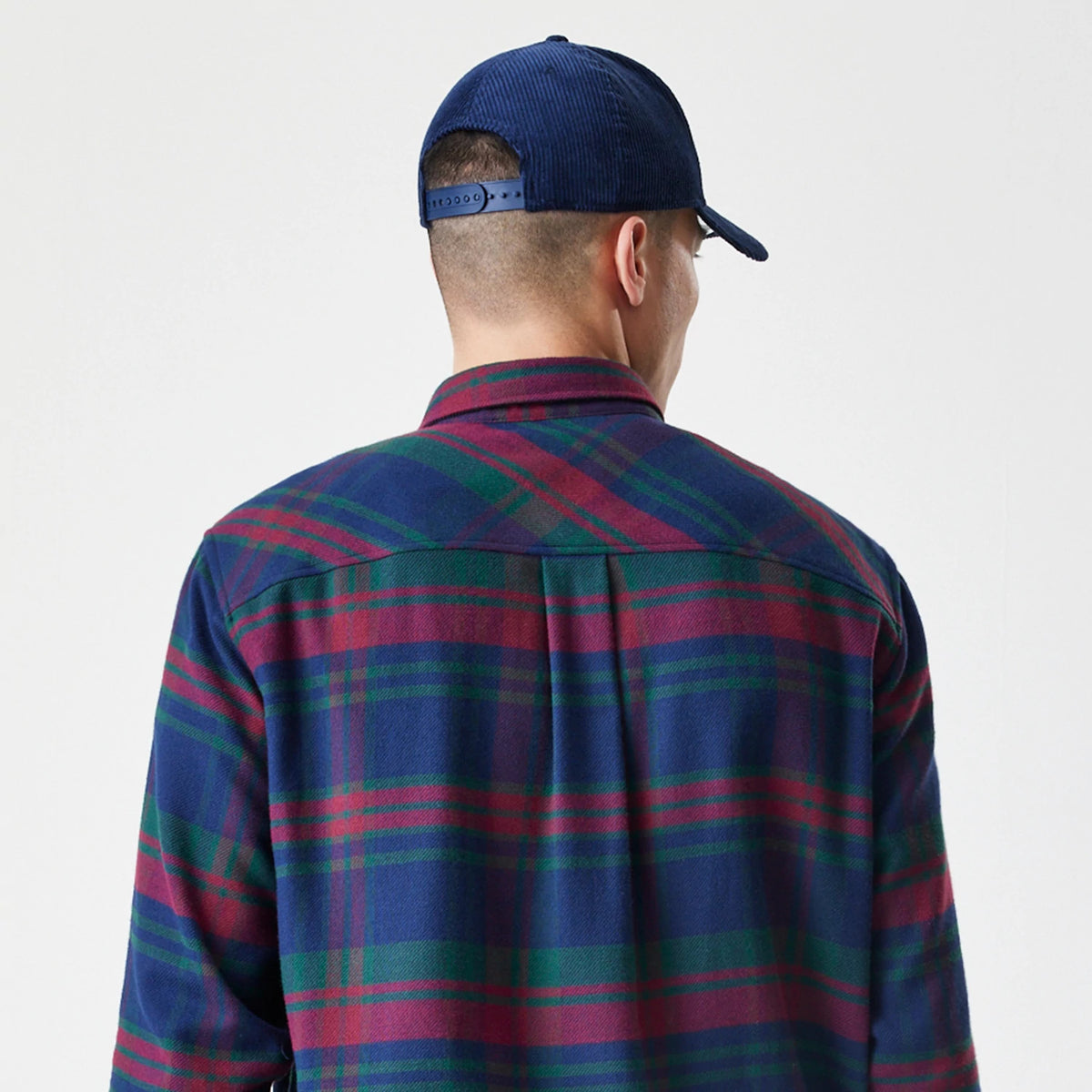 New Era New York Yankees MLB Check Navy Long Sleeve Shirt, back view on a model wearing a navy cap, showcasing the shirt's navy, red, and green plaid pattern across the shoulders and back.