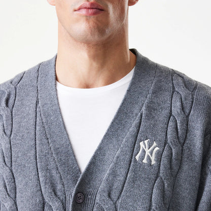 New Era New York Yankees MLB Cable Knit Dark Grey Cardigan, front view on a model showing the intricate cable knit pattern on the dark grey fabric, with an embroidered white NY logo on the left chest above two dark buttons.