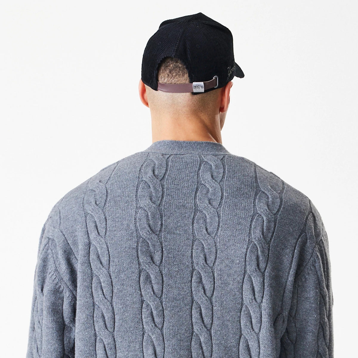 New Era New York Yankees MLB Cable Knit Dark Grey Cardigan, rear view on a model showing the intricate cable knit pattern on the back, highlighting the textured design and rich dark grey colour.