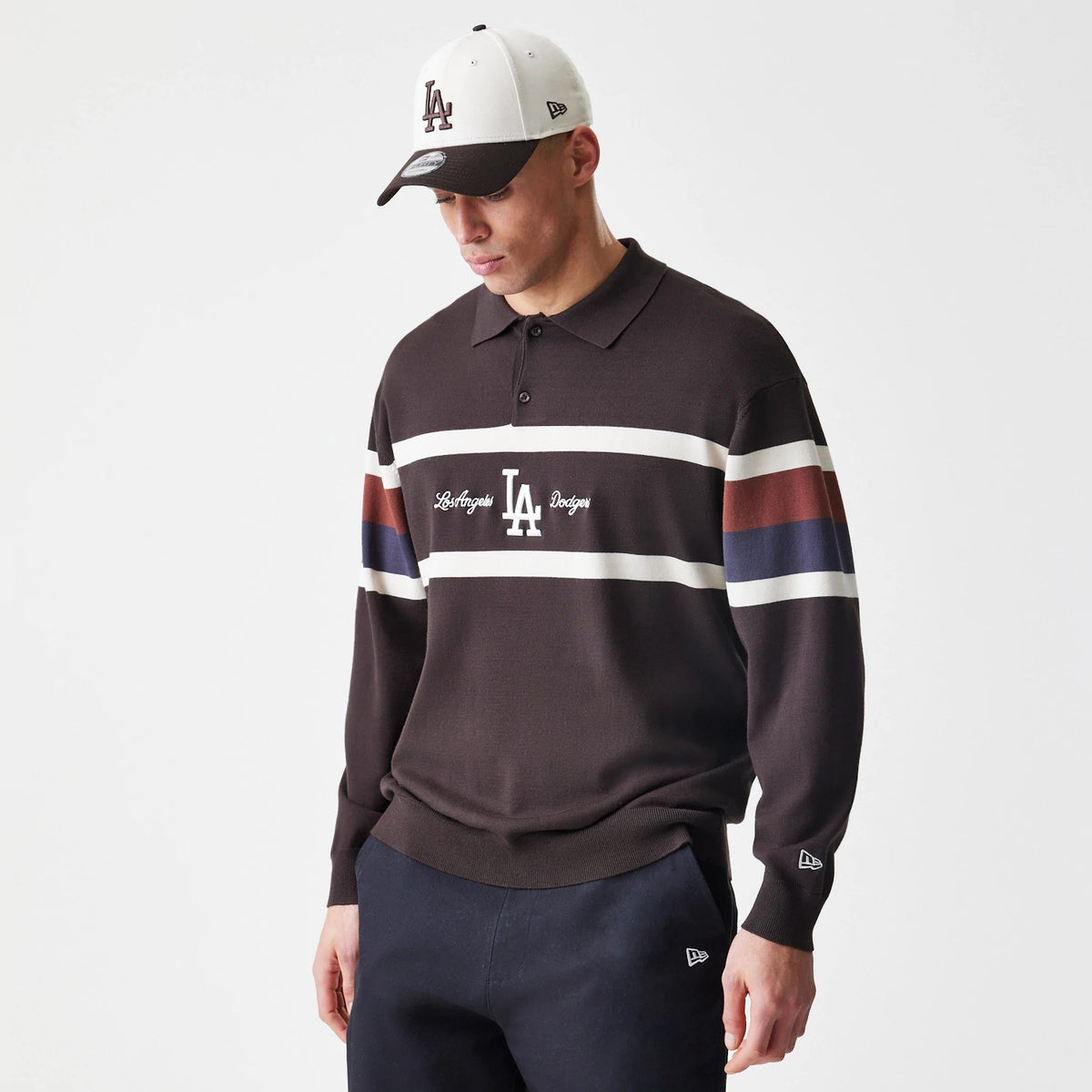 New Era LA Dodgers MLB Knit Brown Rugby Shirt, front view on a model with a white and black cap, showing an embroidered LA logo centred between horizontal stripes across the chest and New Era flag logo on the left sleeve.