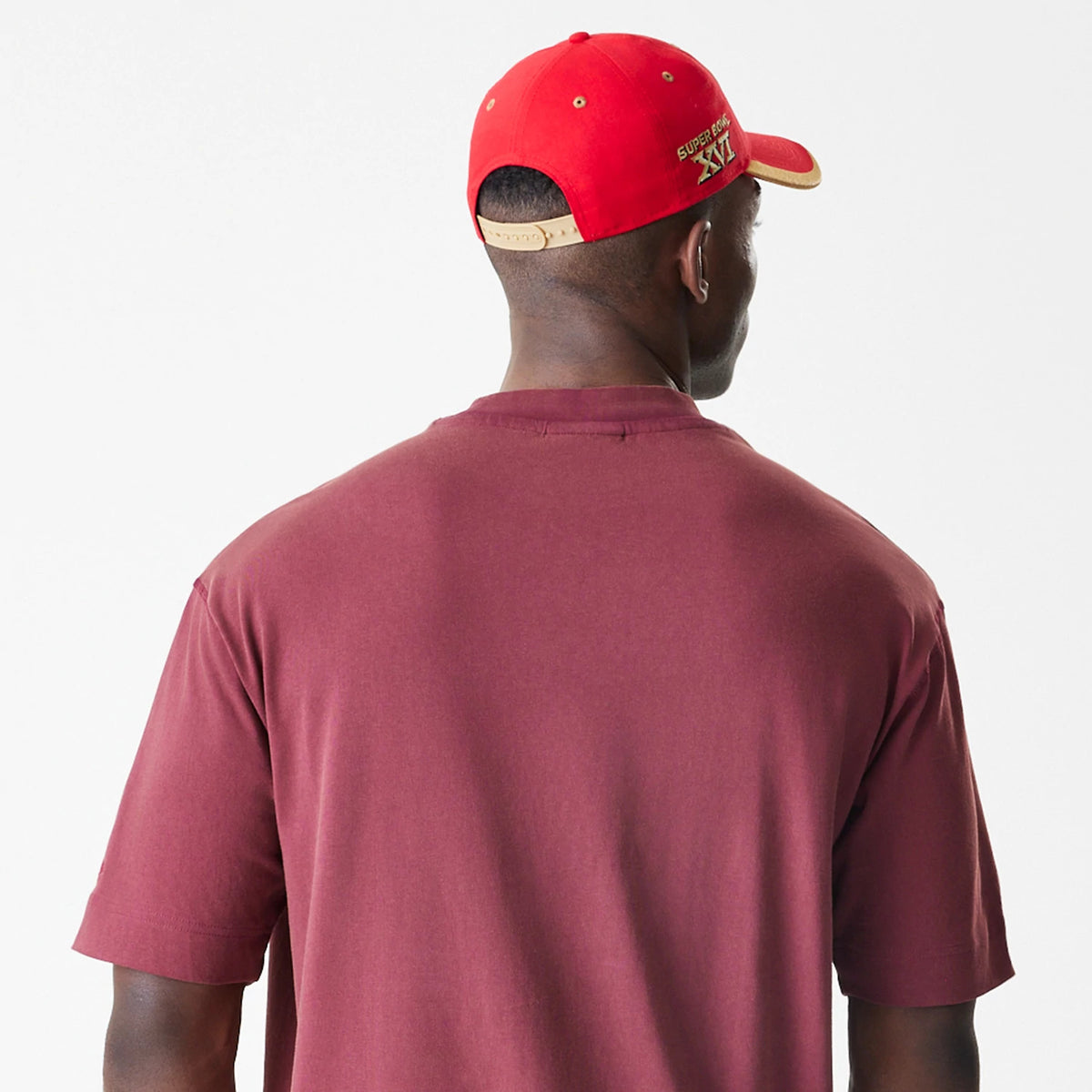 New Era San Francisco 49ers NFL Washed Boxy Dark Red Oversized T-Shirt, back view on-model showing the simple dark red design with loose sleeves, paired with a red cap featuring embroidered gold Super Bowl XVI lettering.