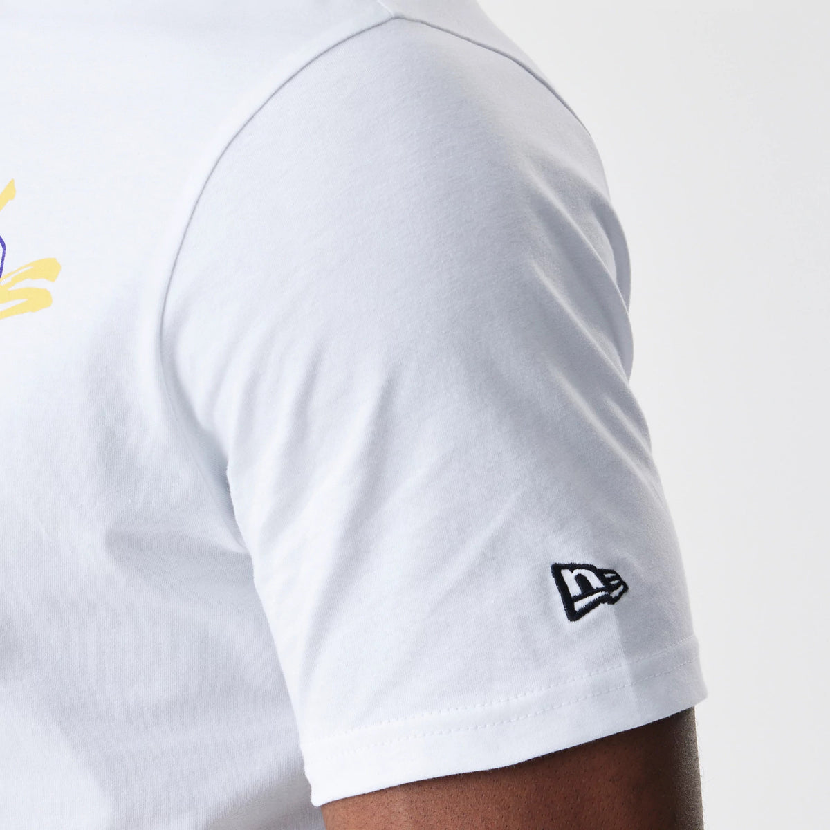 New Era LA Lakers NBA Script White T-Shirt, three-quarter view showing the black embroidered New Era logo on the sleeve and a glimpse of the yellow and purple script graphic on the front.