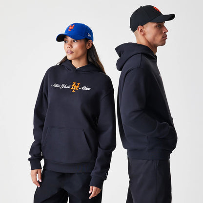 New Era New York Mets MLB Script Black Oversized Pullover Hoodie, front view on models, featuring New York Mets embroidered script and logo in white and orange on the chest, styled with a blue cap and a black cap.