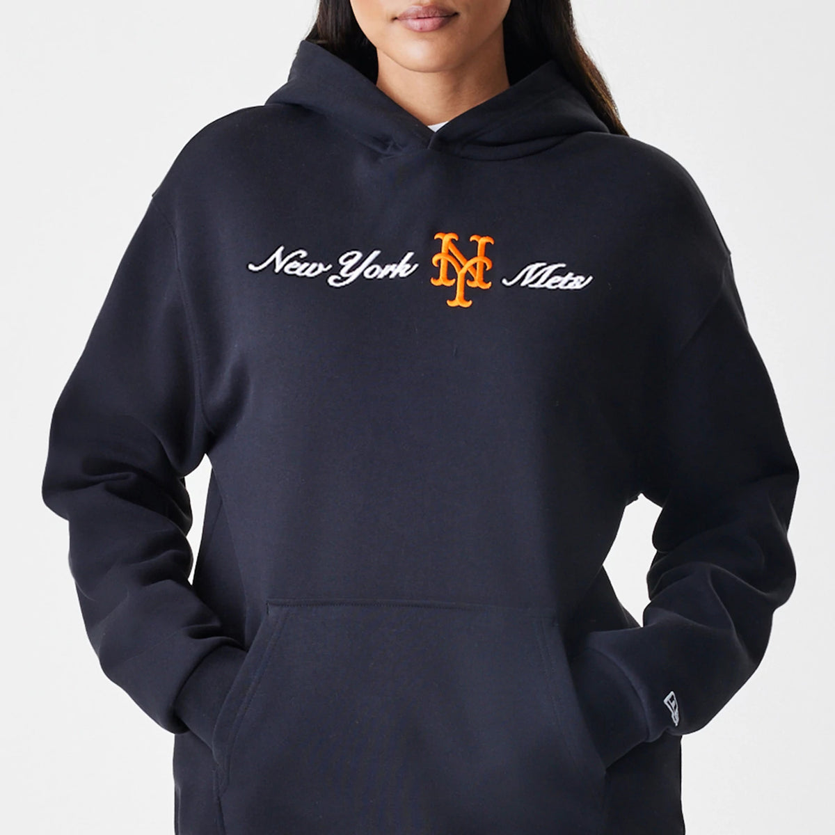New Era New York Mets MLB Script Black Oversized Pullover Hoodie, front view on-model showing white embroidered 'New York Mets' script across the chest with an orange Mets logo in the centre, and a small embroidered New Era logo on the left cuff.