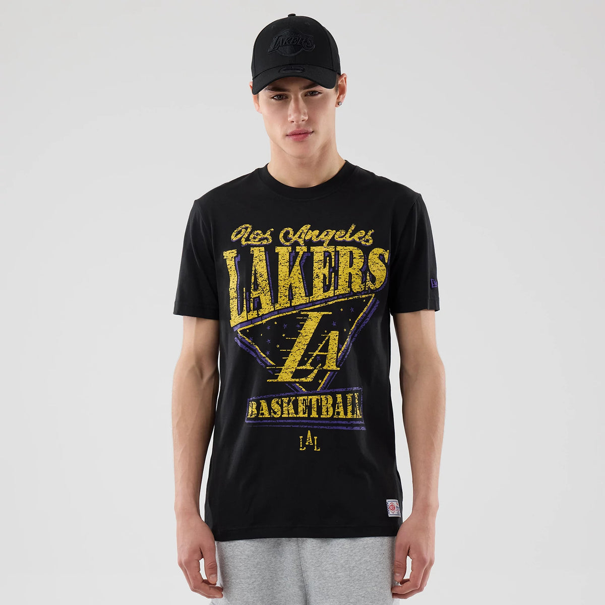 New Era LA Lakers NBA City Edition Black T-Shirt, front view on-model showing large distressed gold and purple Lakers graphic on the chest, small LA logo near the hem, and embroidered New Era logo on the sleeve.